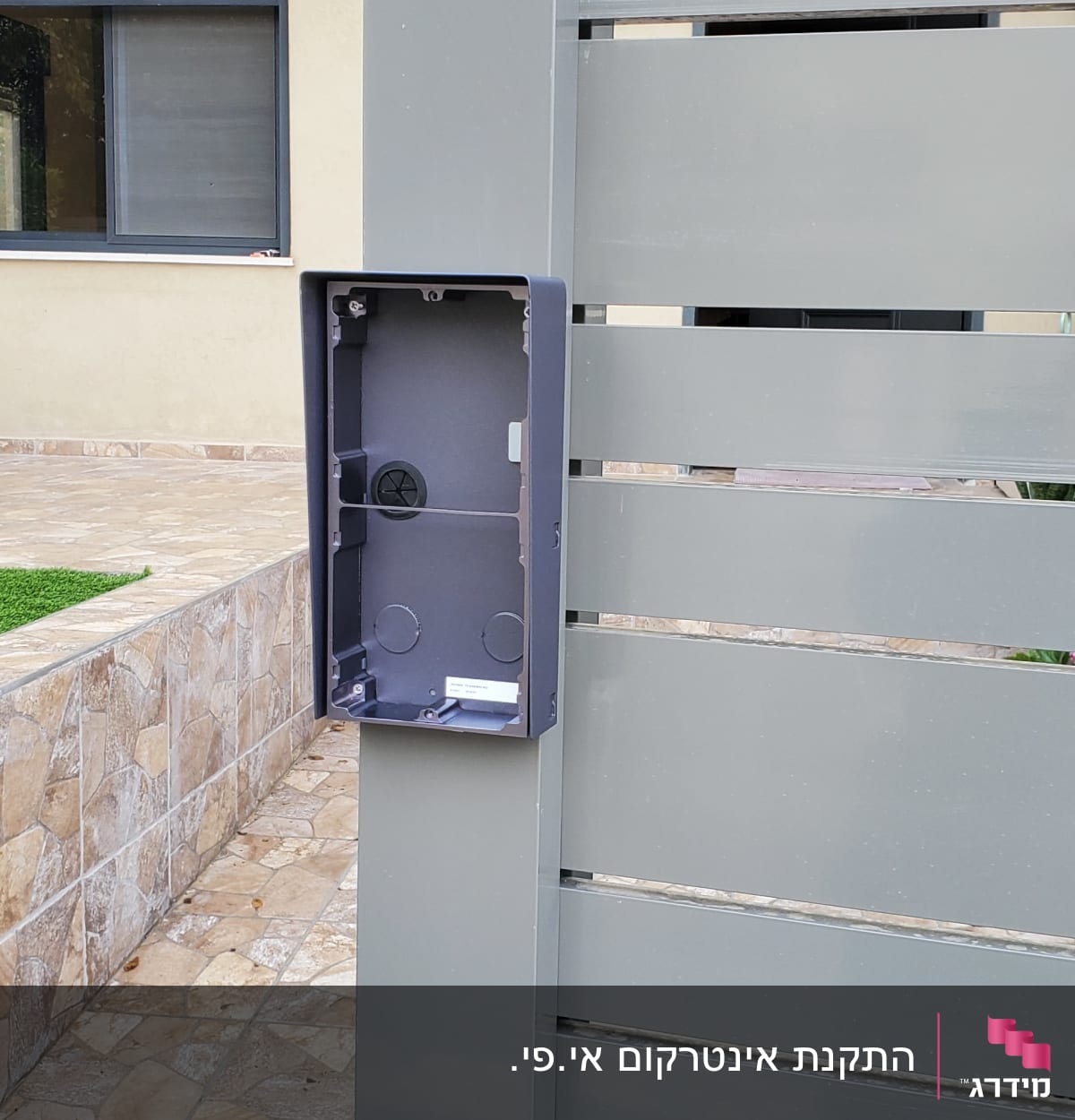 תיבת אינטרקום ריקה מותקנת על גדר מתכת אפורה